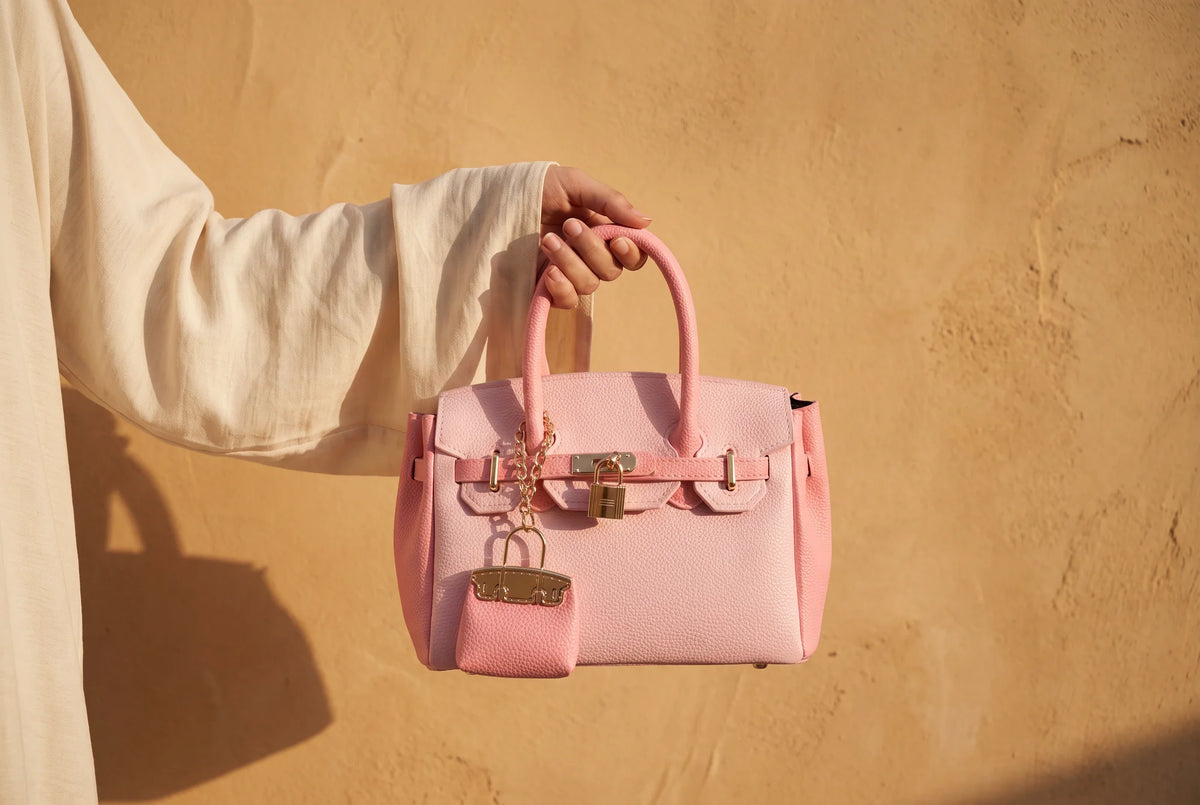 Blush Lola bag held through a torn paper backdrop